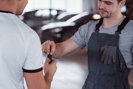 Mechanic gives keys to the owner of the repaired car in the workshop.の写真素材