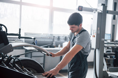 Let this machine do the job. Young man works with wheels disks at the workshop at daytime.