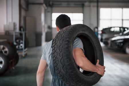 Going forward. Mechanic holding a tire at the repair garage. Replacement of winter and summer tires.の写真素材