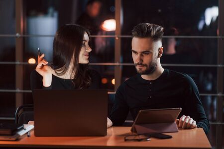 Front view. Team of young business people works on their project at night time in the office.の写真素材
