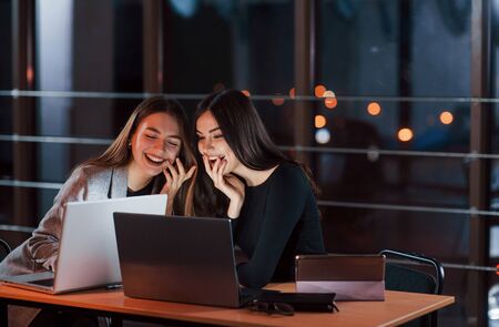 Laughing together. Team of young business people works on their project at night time in the office.の写真素材