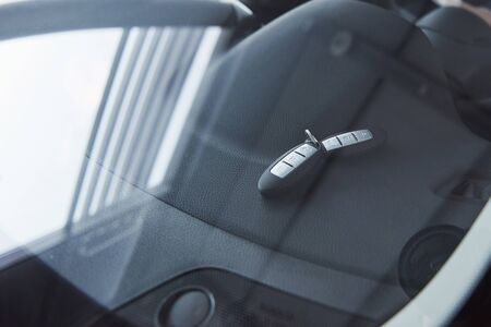 Automobile keys lying on the front panel of the car that captured through the window.の写真素材