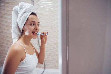 Teeth health care. In the bathroom. Woman in white towel in head have care of herself.の写真素材
