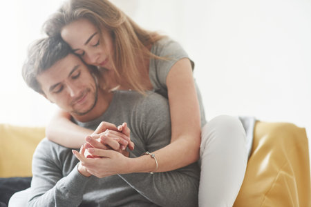 Natural lighting. Happy couple relaxing on the yellow sofa in the living room of their new house.