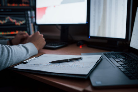 Close up view. Man working online in the office with multiple computer screens in index charts.