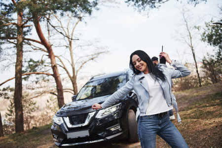 Morning streching. Couple have arrived to the forest on their brand new black car.