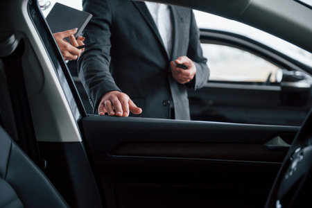 Photo from the inside of vehicle. Female customer and modern stylish bearded businessman in the...