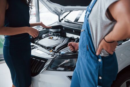 Well take care of this. Woman in the auto salon with employee in blue uniform taking her repaired car back.の写真素材