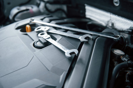 Repair tools lying down on the engine of automobile under the hood.