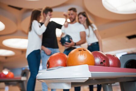 Many different colored balls. Young cheerful friends have fun in bowling club at their weekends.の写真素材