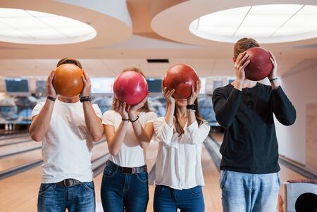 Different colors. Young cheerful friends have fun in bowling club at their weekends.の写真素材