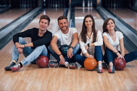 Good time spending. Young cheerful friends have fun in bowling club at their weekends.の写真素材