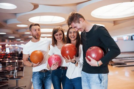 Joking around. Young cheerful friends have fun in bowling club at their weekends.の写真素材