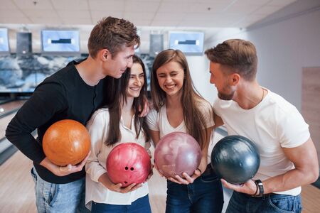 Funny joke. Young cheerful friends have fun in bowling club at their weekends.の写真素材
