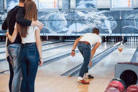 Rolling ball. Young cheerful friends have fun in bowling club at their weekends.の写真素材