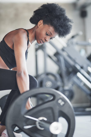 Giving her best. African american woman with curly hair and in sportive clothes have fitness day in...