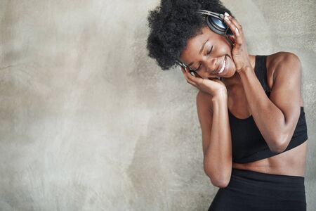 Feel the music. Portrait of african american girl in fitness clothes having a break after workout.の写真素材