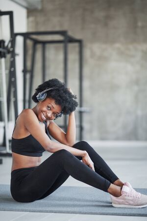 Happy girl. African american woman with curly hair and in sportive clothes have fitness day in the gym.の写真素材