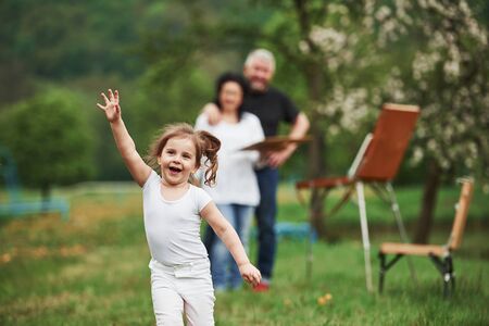 Running forward. Grandmother and grandfather have fun outdoors with granddaughter. Painting conception.の写真素材