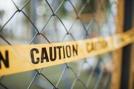 Do not enter. Yellow caution tape on the metal fence at daytime. Crime scene.の写真素材