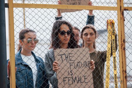 With yellow colored caution tape. Group of feminist women have protest for their rights outdoors.の写真素材