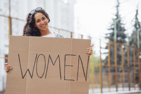 Pretty girl with curly hair stands with handmade feminist poster in hands.の写真素材