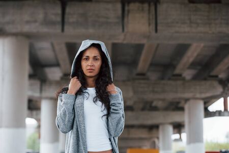 Stylish girl. Portrait of beautiful young woman standing under the bridge outdoors.の写真素材