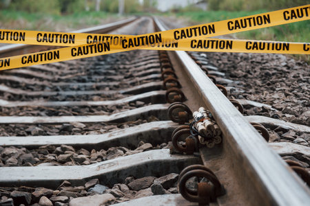 Be aware. Dangerous explosive lying on the railway. Yellow caution tape in front.