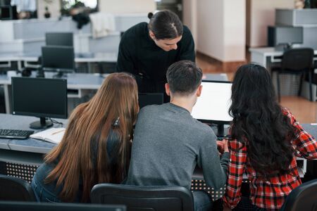 Together near one monitor. Group of young people in casual clothes working in the modern office.の写真素材
