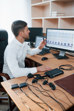 Vertical photo. Polygraph examiner works in the office with his lie detectors equipment.