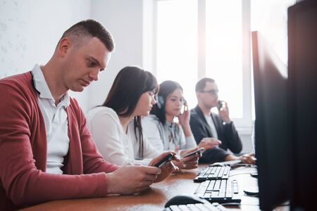 With smartphones in hands. Young people working in the call center. New deals is coming.の写真素材