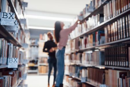 Blurred photo. Multiracial students in the library searching for the information together.の写真素材