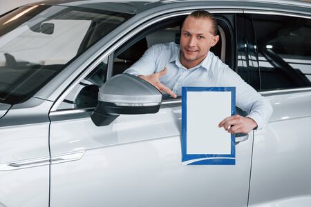 Conception of business. Manager sitting in modern white car with paper and documents in hands.の写真素材