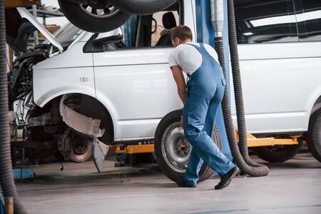 Replacement of tyres. Employee in the blue colored uniform works in the automobile salon.の写真素材