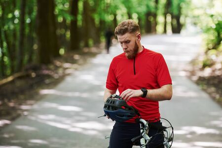 Safety first. Cyclist on a bike is on the asphalt road in the forest at sunny day.の写真素材
