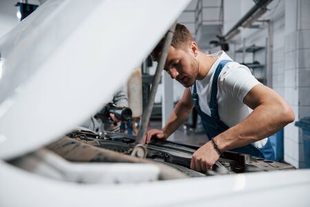 Concentrated look. Employee in the blue colored uniform works in the automobile salon.の写真素材