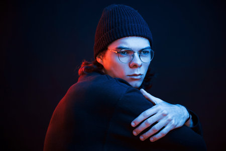 Thinking about some problems. Studio shot in dark studio with neon light. Portrait of serious man.