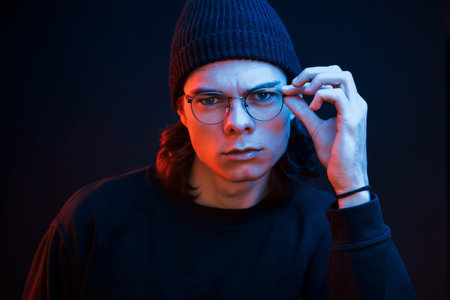 Smart person. Studio shot in dark studio with neon light. Portrait of serious man.
