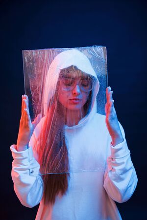 Alone in the room. Studio shot in dark studio with neon light. Portrait of young girl.の写真素材