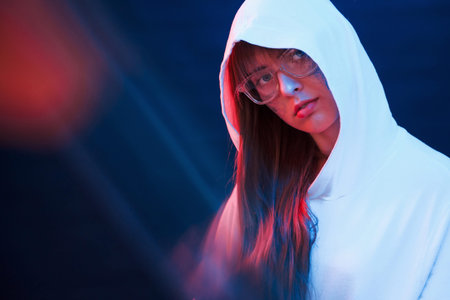 Caucasian ethnicity. Studio shot in dark studio with neon light. Portrait of young girl.