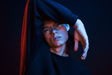 Having leisure. Studio shot in dark studio with neon light. Portrait of serious man.