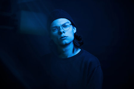 Cold color. Studio shot in dark studio with neon light. Portrait of serious man.
