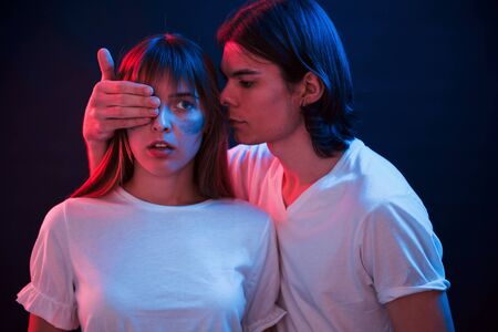 I have surprise for you. Couple standing in dark room with red and blue neon lighting.の写真素材
