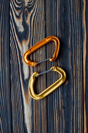 Two objects. Isolated photo of climbing equipment. Parts of carabiners lying on the wooden table.