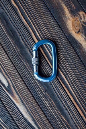 Steel material. Isolated photo of climbing equipment. Part of carabiner lying on the wooden table.の写真素材
