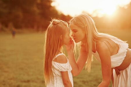 Let me take away that thing. Mother and daughter enjoying weekend together by walking outdoors in the field. Beautiful nature.の写真素材