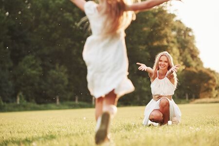 Into the mothers hands. Woman and her daughter enjoying weekend together by walking outdoors in the field. Beautiful nature.の写真素材
