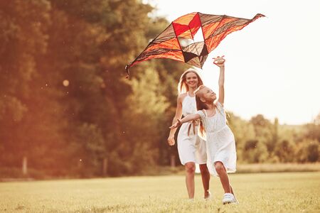 Summer sunny day. Mother and daughter have fun with kite in the field. Beautiful nature.の写真素材