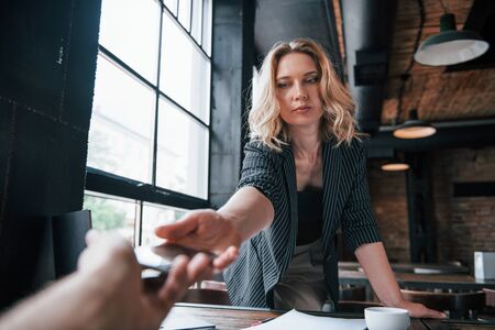 Taking smartphone from the hand of patient. Businesswoman with curly blonde hair indoors in cafe at daytime.の写真素材