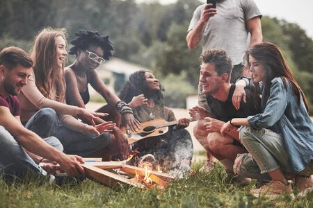 Rest near campfire. Group of people have picnic on the beach. Friends have fun at weekend time.の写真素材